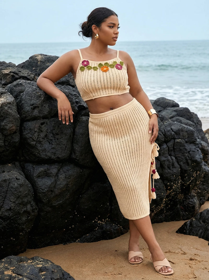 Woman in a beige knit outfit standing on a rocky beach.