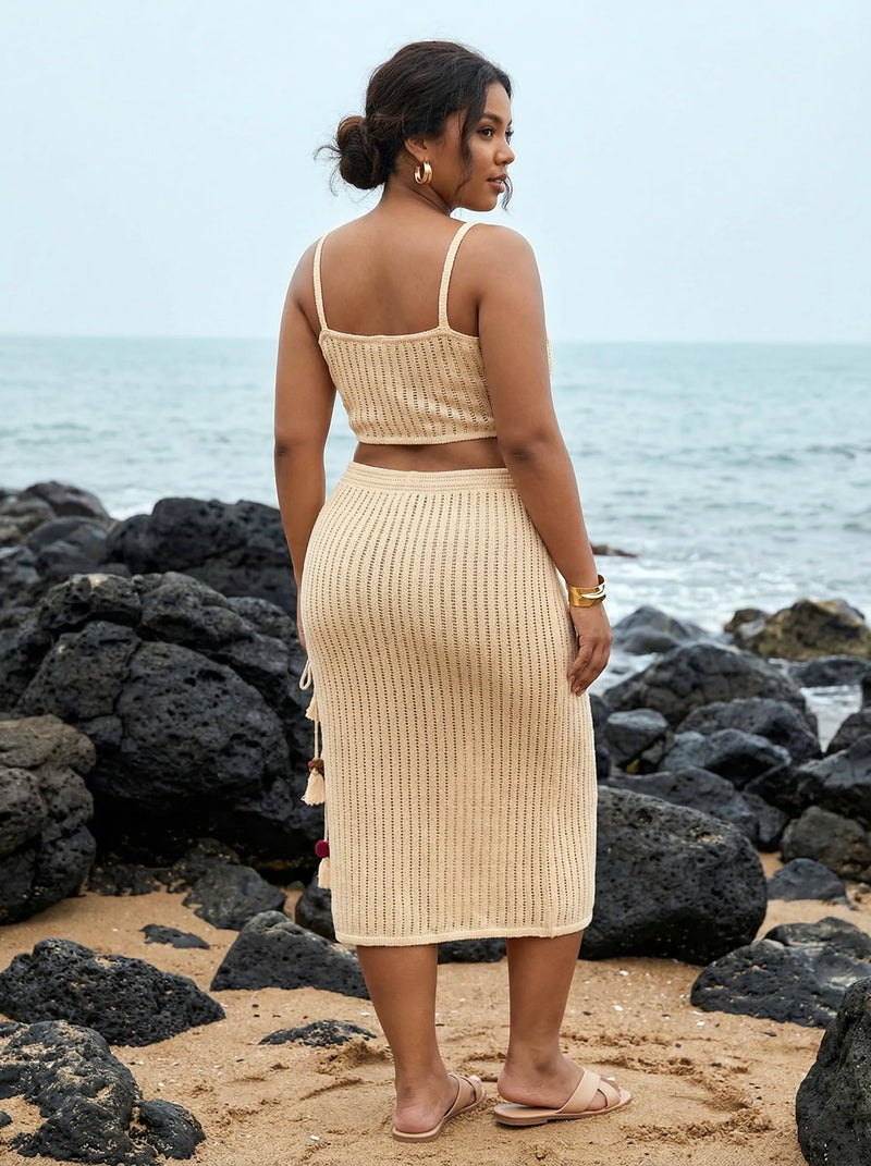 Woman in a beige ribbed dress standing on a rocky beach with ocean view